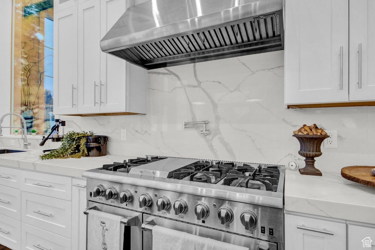 A sleek, modern kitchen design is showcased in this photograph, its clean lines and luxurious marble countertops emphasized. The large window floods the space with natural light, highlighting the high-end appliances and fixtures.