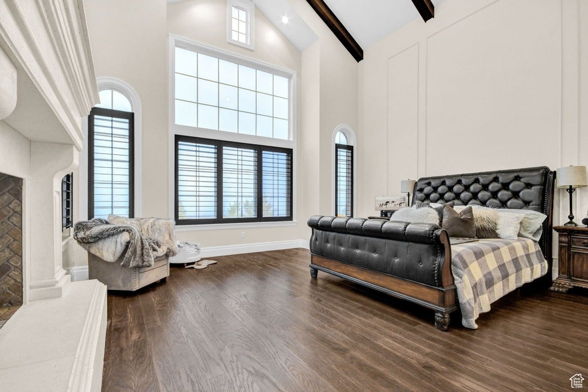 This master bedroom is presented in a photograph that emphasizes its spaciousness and elegant design. The high ceilings, large windows, and dark wood floors create a sense of grandeur, complemented by the luxurious sleigh bed as a central feature.