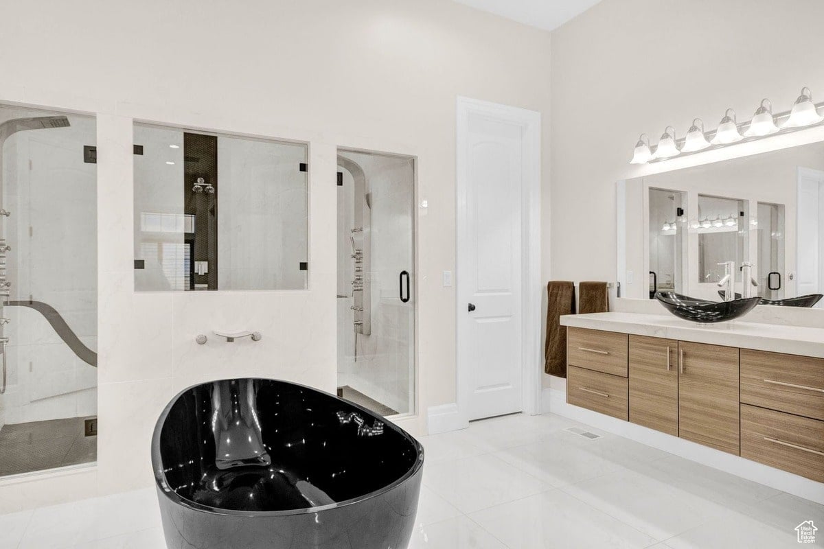 This master bathroom's design is showcased in a photograph that emphasizes its spaciousness and high-end features. The black soaking tub, multiple shower areas, and elegant vanity create a luxurious and relaxing environment.