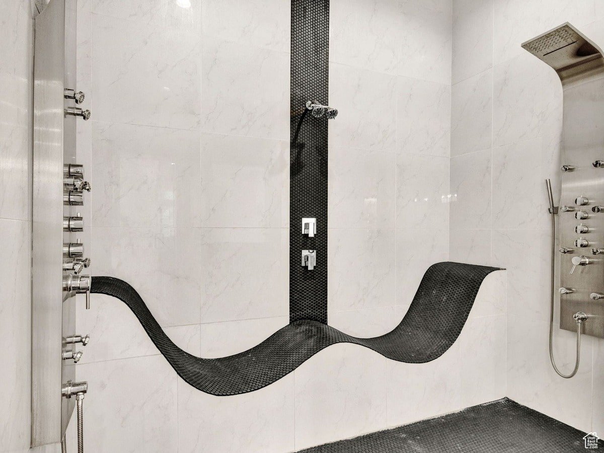 A detail of a high-end bathroom is presented in the photograph, with the focus on a sculptural shower and its wave-like seat. Contrasting materials and multiple showerheads combine to produce a modern, luxurious, spa-like atmosphere.