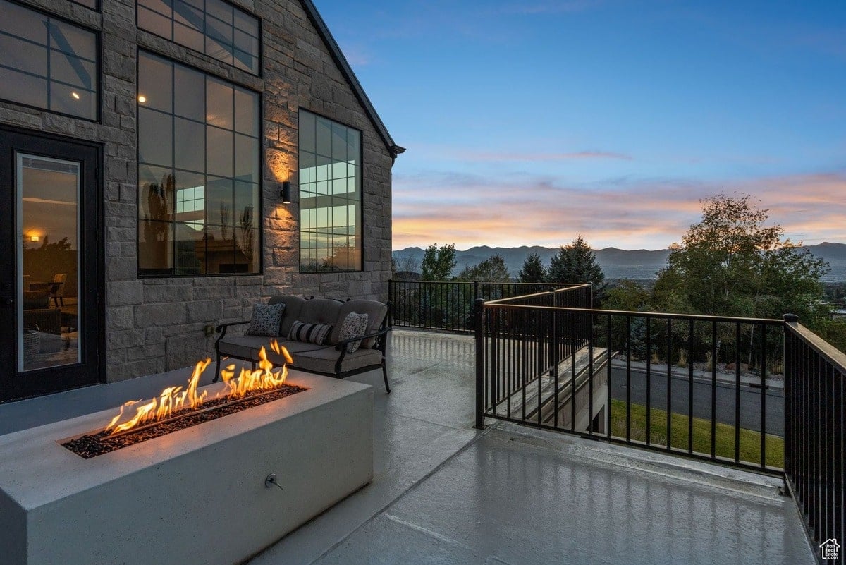 A rooftop patio offers a stunning sunset view, complete with a comfortable seating area and a modern fire pit. The scene is captured from a wide angle, showcasing the expansive vista and tranquil atmosphere.