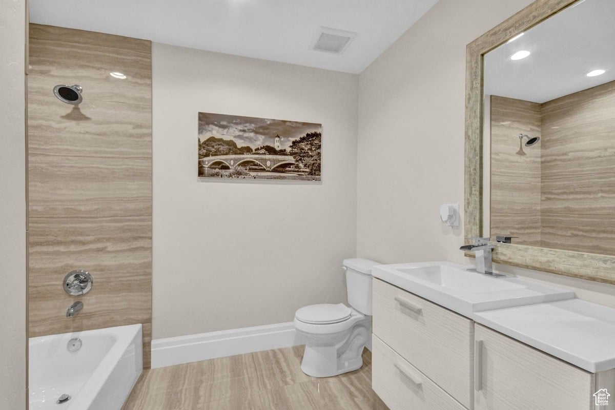 This bathroom features a serene design with a neutral color palette, incorporating a textured wall and a modern vanity. A framed landscape print adds a touch of visual interest above the toilet, creating a calming atmosphere.