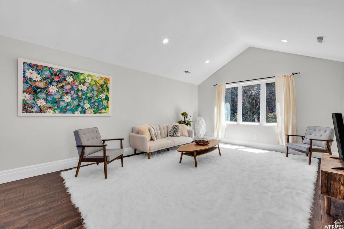 A relaxing living area is presented, with a light and airy atmosphere created by the large windows and neutral color palette. The mid-century modern furniture and statement artwork create a sophisticated and inviting space.