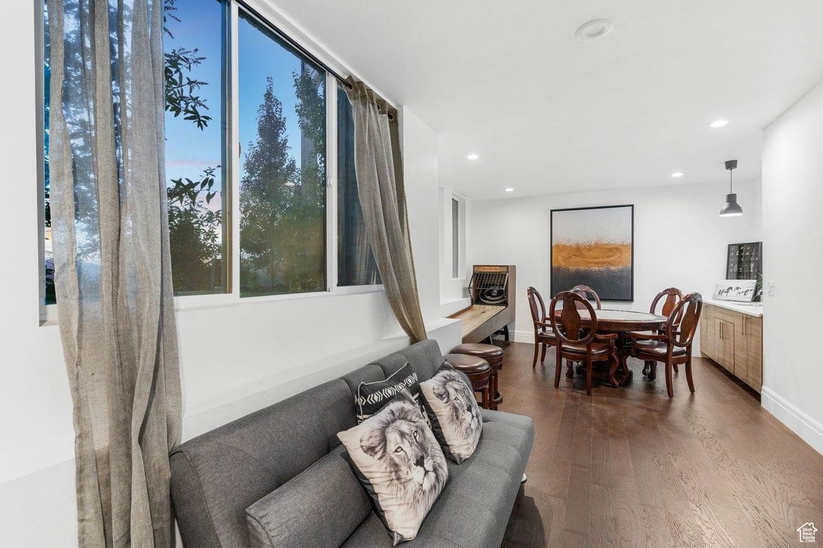 A versatile space is presented, seamlessly blending a comfortable lounge area with a formal dining setting. The room's design incorporates natural light and neutral tones, creating a relaxed yet sophisticated ambiance.