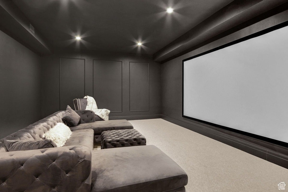 A modern home theater is highlighted, featuring a large screen and a plush sectional sofa with tufted upholstery. The dark walls and ambient lighting create an intimate and luxurious atmosphere for movie viewing.
