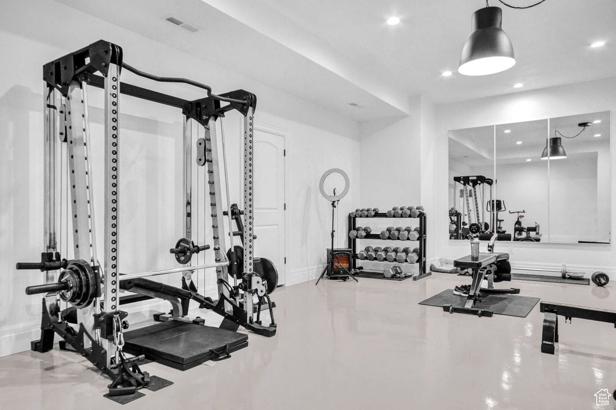 A well-equipped home gym is showcased, featuring a power rack, dumbbell rack, and weight bench. The bright, minimalist design creates a clean and motivating workout space.