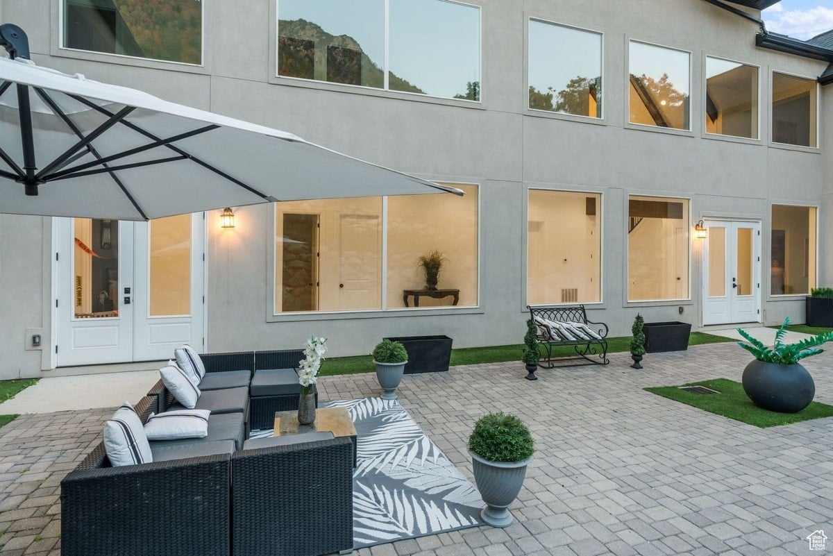 A modern home's backyard patio is shown, featuring a stylish seating area under a large umbrella and a paved courtyard. The design incorporates potted plants and a neutral color palette, creating a serene and sophisticated outdoor space.