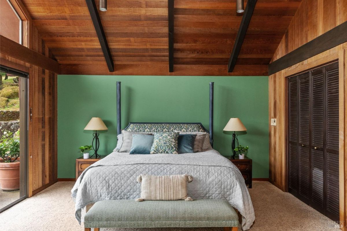 Cozy bedroom showcases a green accent wall, wooden elements, and elegant furnishings.