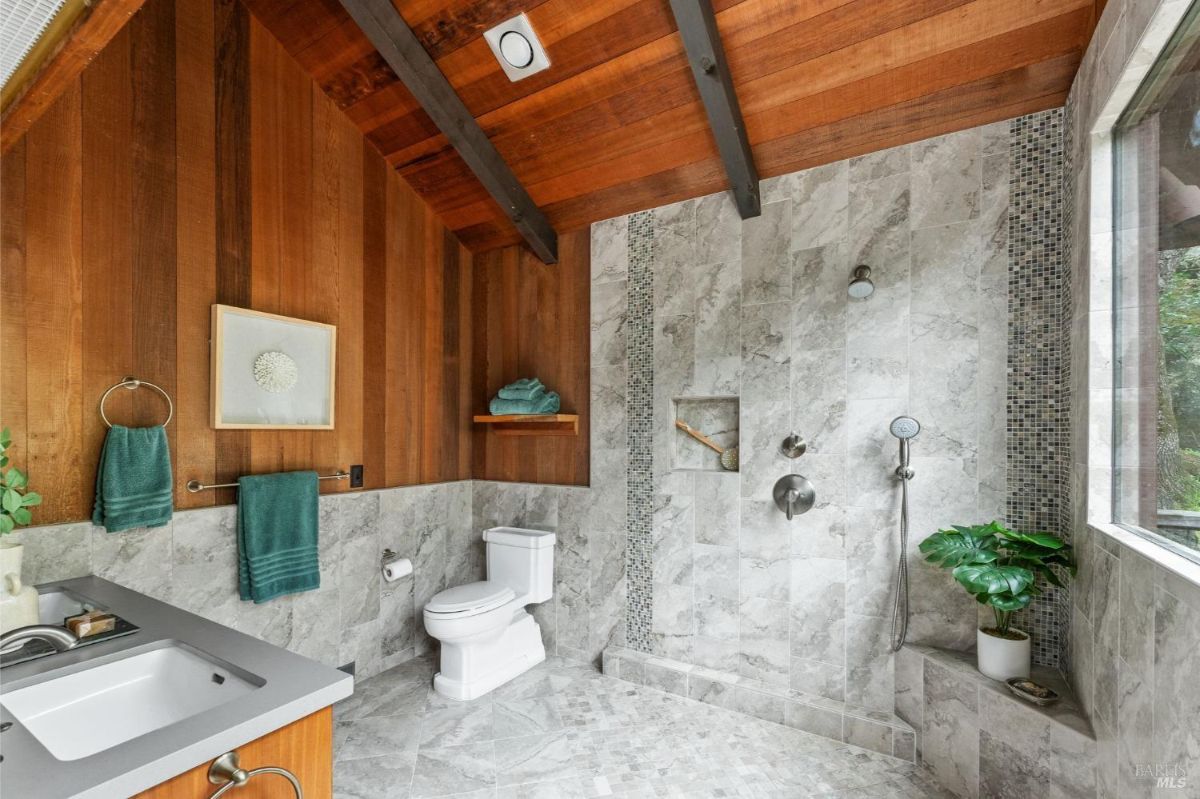 Luxurious bathroom features marble tiles, a spacious walk-in shower, and natural wood finishes.