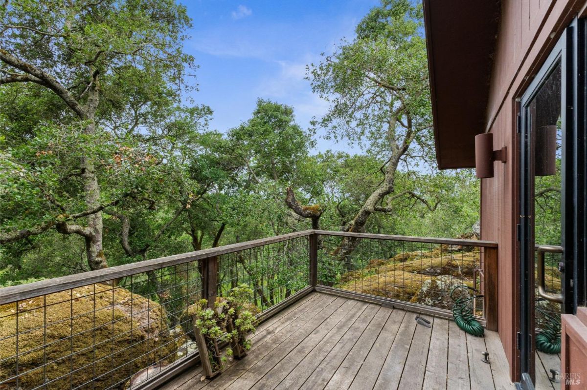 Elevated wooden deck overlooks a peaceful forest, offering a serene retreat amid lush greenery.