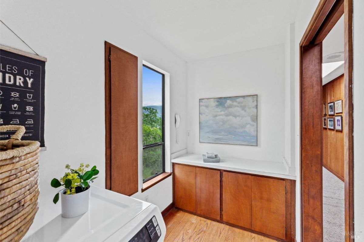 Laundry area features a clean design with wooden cabinetry, a scenic window, and simple decor.