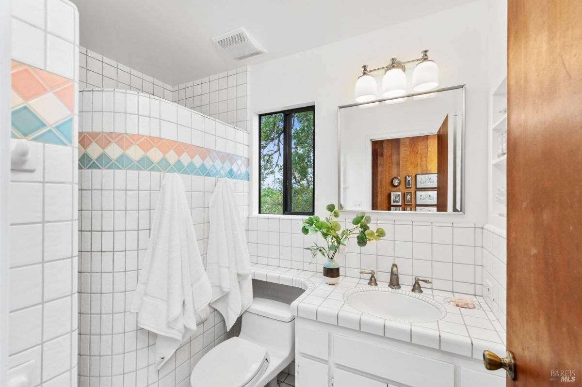 Colorful tiled bathroom includes vibrant diamond-patterned accents and a large vanity mirror.