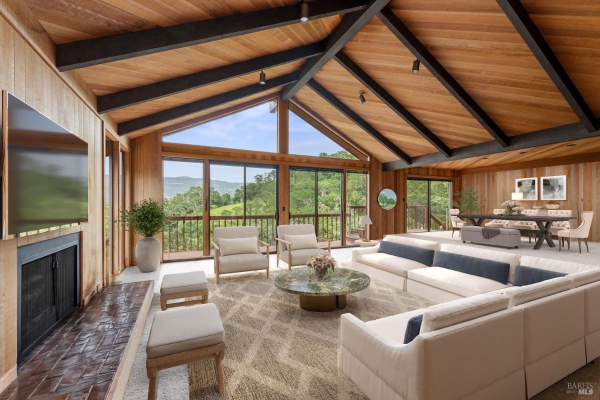 Spacious living room with exposed wooden beams, panoramic windows, and comfortable modern seating.