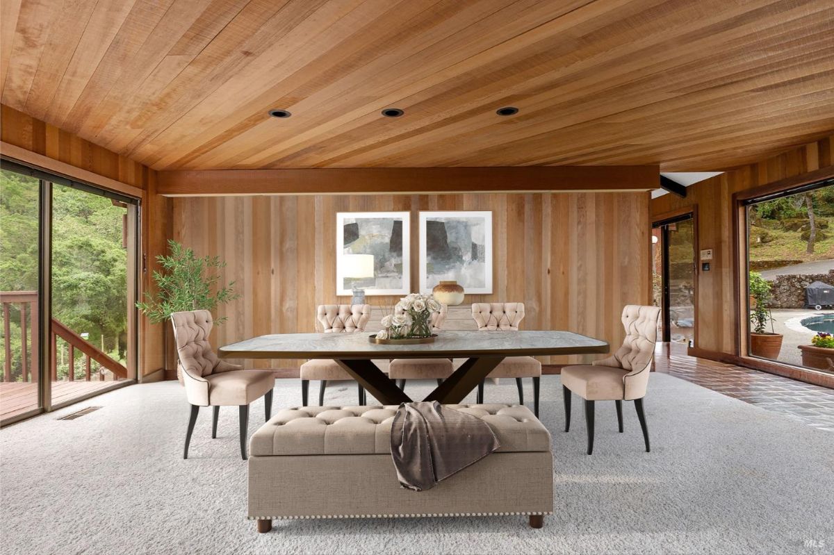 Dining room featuring a wooden ceiling, tufted chairs, and natural light from surrounding glass doors.