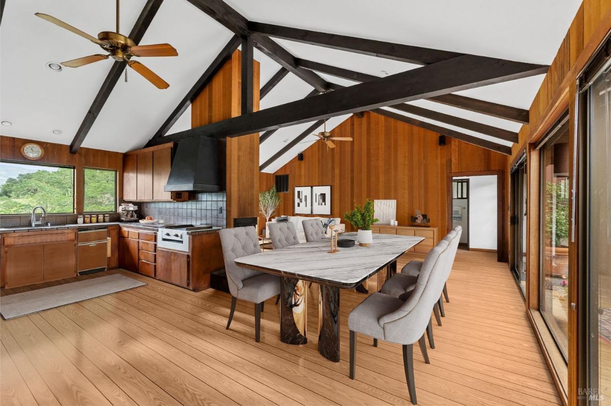 Open-concept kitchen and dining area with a vaulted ceiling, ceiling fans, and a mix of wood and glass elements.