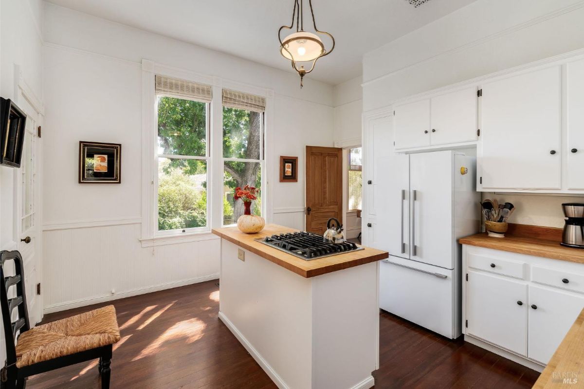 Kitchen with white cabinets, wooden countertops, and an island with a stovetop.