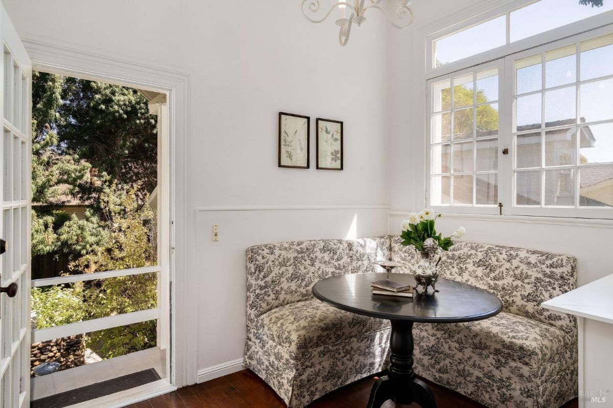Small breakfast nook with a patterned bench, round table, and a door leading to a garden.