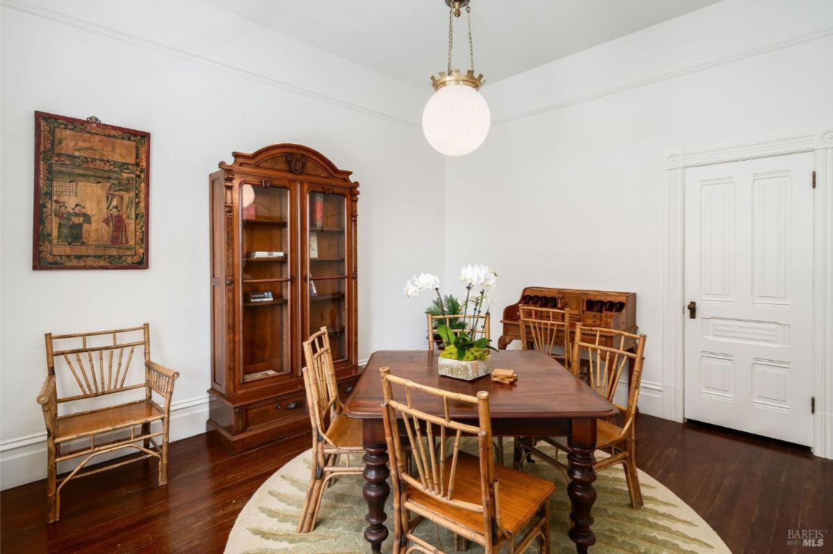 Dining room with antique furniture, a wooden table, bamboo chairs, and a display cabinet.