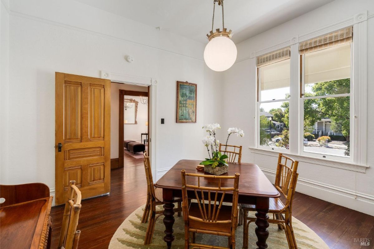 Dining room with a wooden table, bamboo chairs, and large windows.