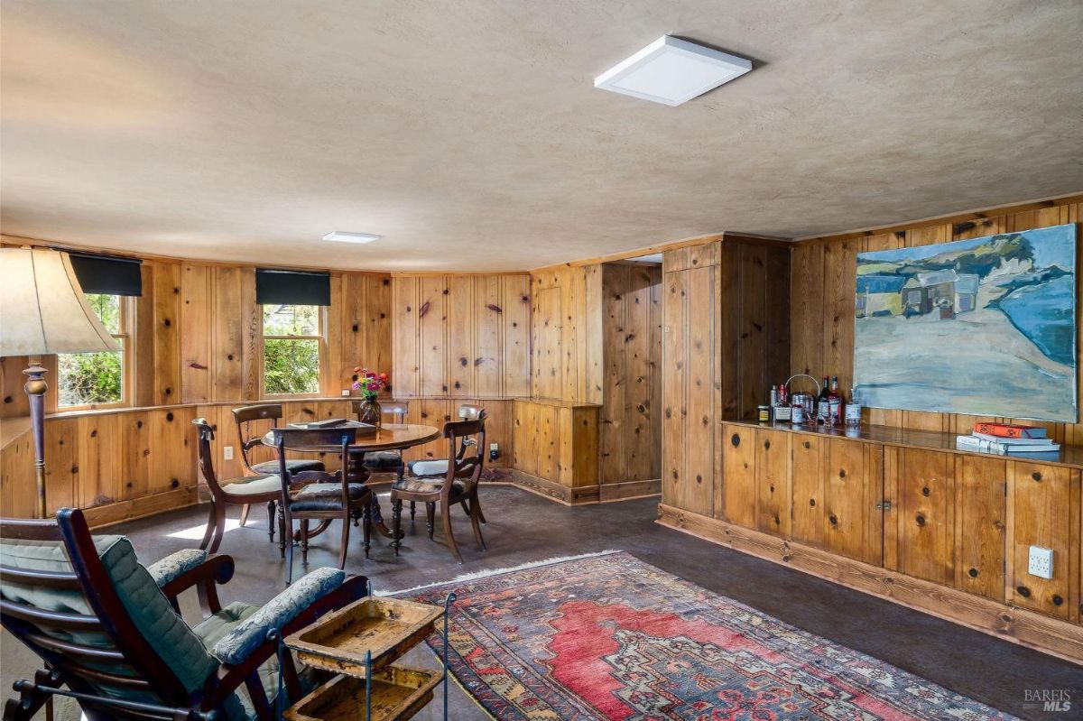 Cozy wooden-paneled room with a dining table, chairs, and built-in bar.