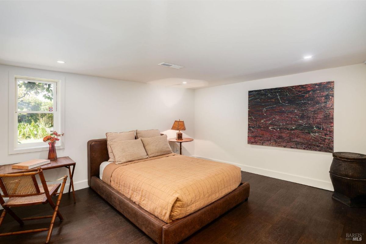 Bedroom with a low bed, a side table, and a large abstract painting mounted on the wall.