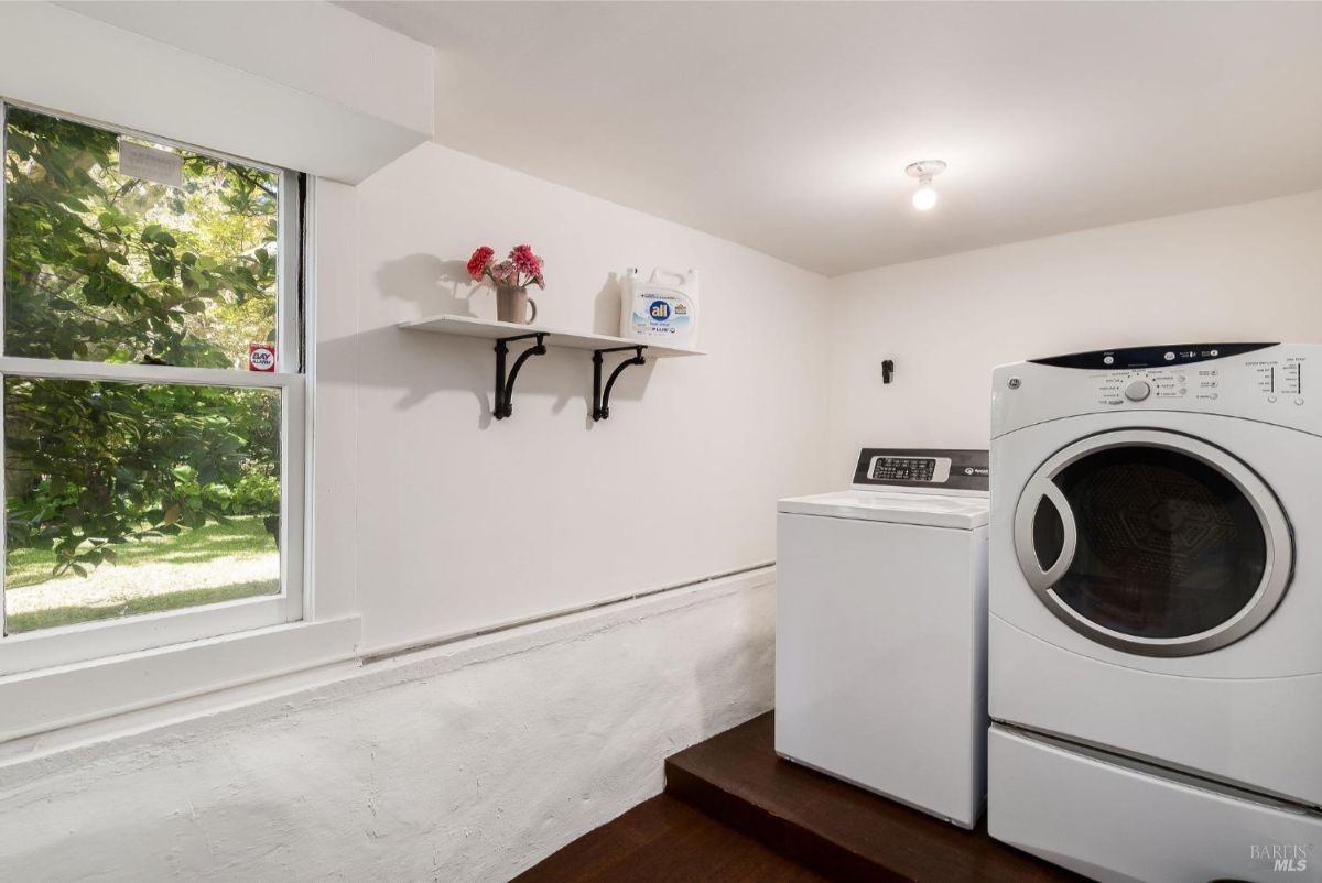 Laundry room includes a washing machine, dryer, and a window providing natural light.