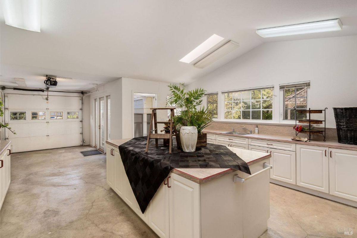 Spacious utility room featuring a long countertop, multiple cabinets, and natural light from several windows.