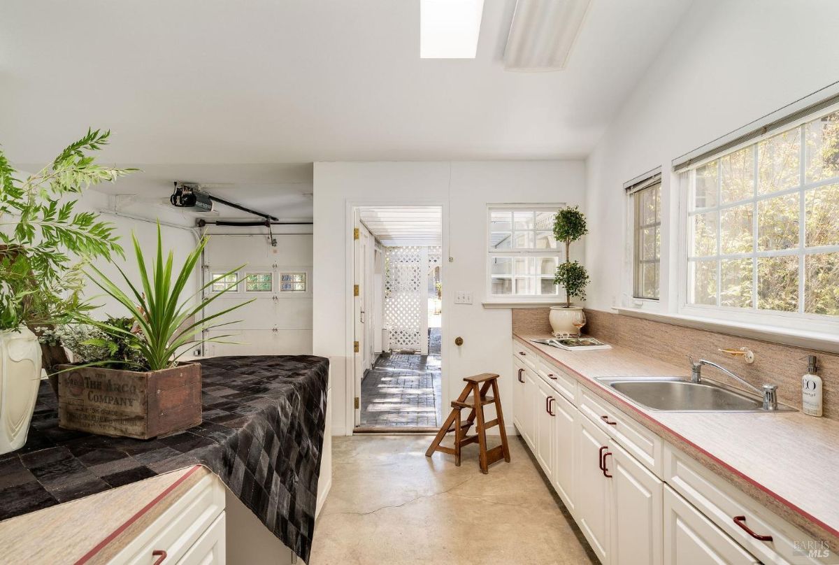 Garage area connected to a utility space with countertops, a sink, and multiple windows.