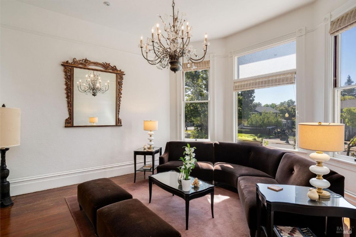 Living room with a decorative mirror and windows allowing natural light.