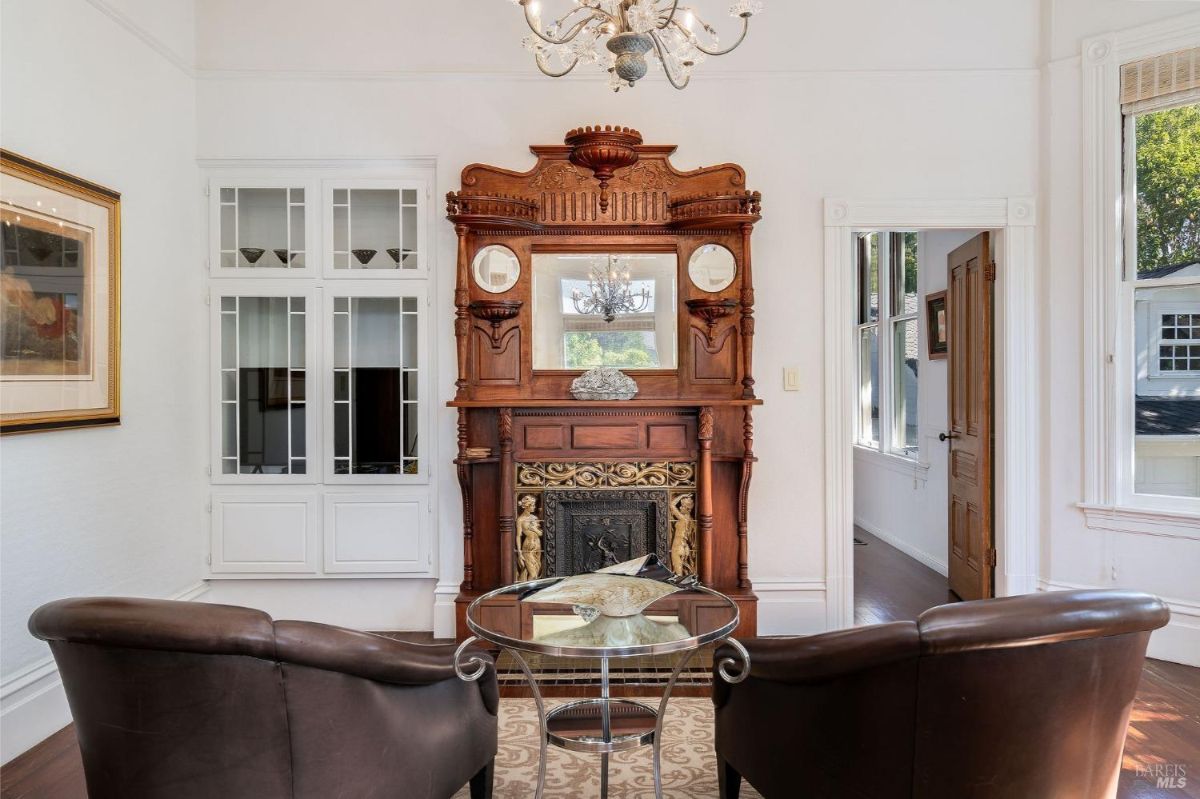 Ornate fireplace with a wooden mantle and decorative mirror in a sitting area.