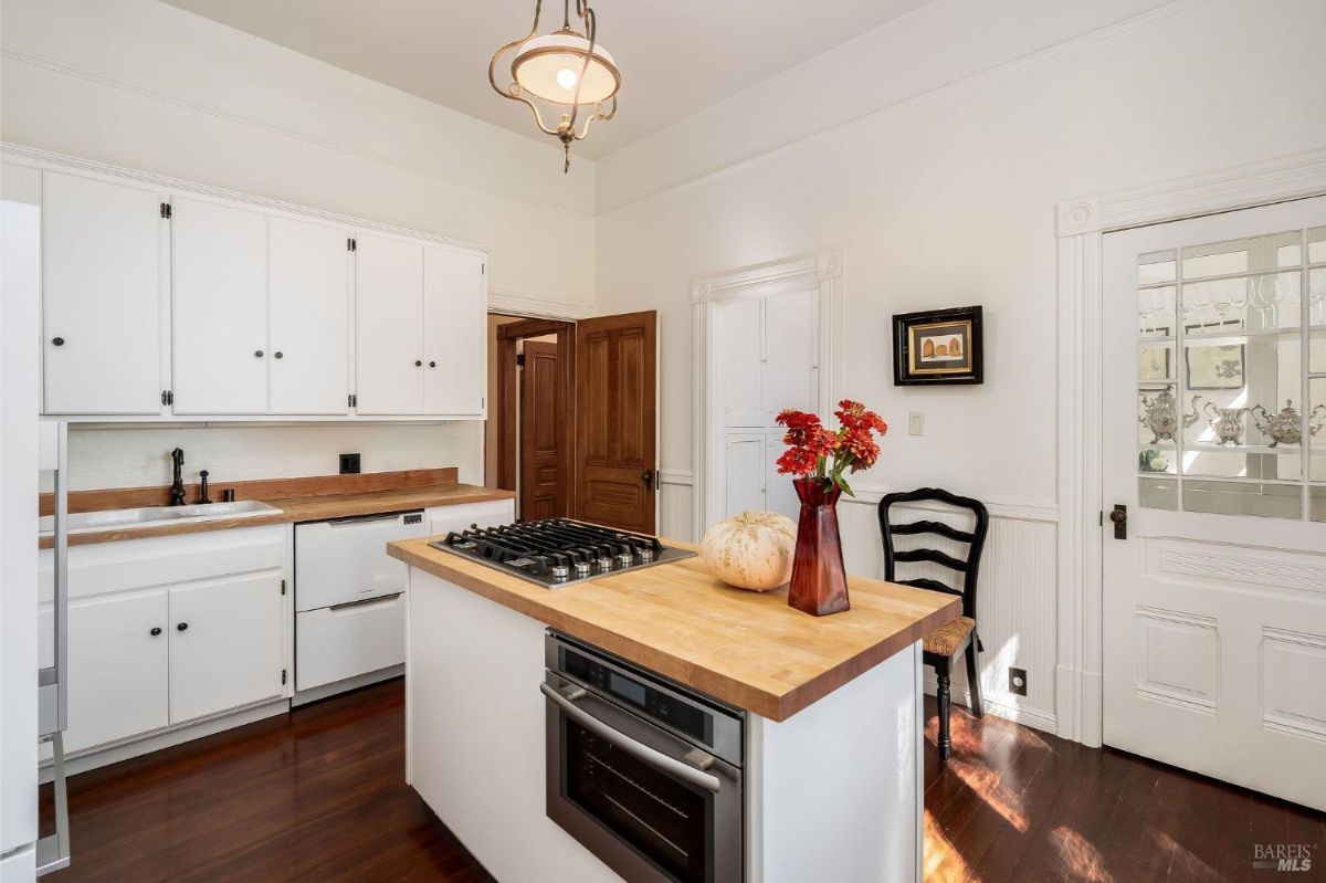 Alternate kitchen view showing a stove, sink, and a door leading to another room.