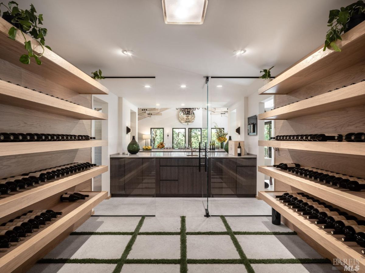 A wine cellar featuring wooden shelving stocked with bottles, leading to a modern lounge area. The space is well-lit, combining functionality with style for wine storage and entertaining.