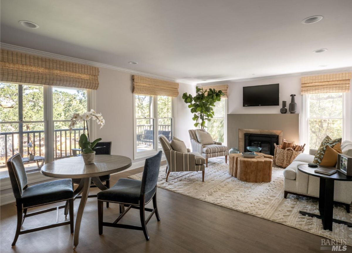 A stylish and comfortable family room with large windows, a fireplace, a circular coffee table, and a mix of modern and traditional furniture, perfect for relaxation and gatherings.