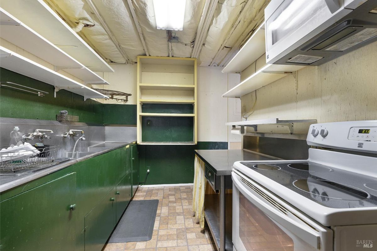 A small kitchen area with green cabinets, metal countertops, and white appliances.