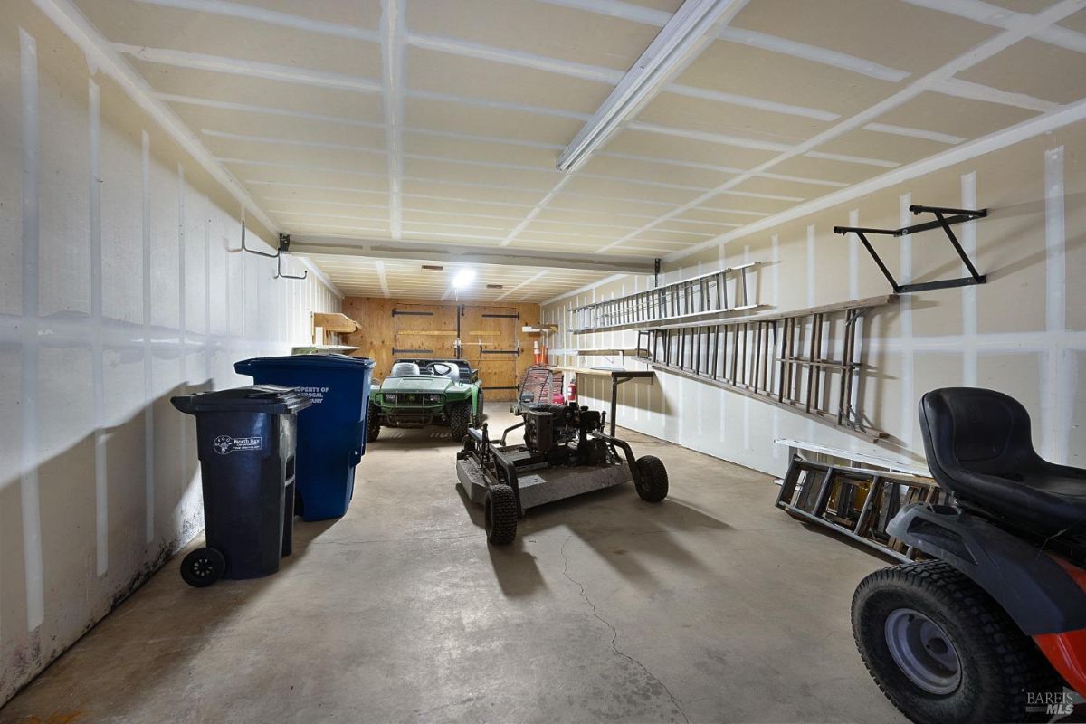 Garage interior with parked vehicles, tools, and organized storage along the walls.
