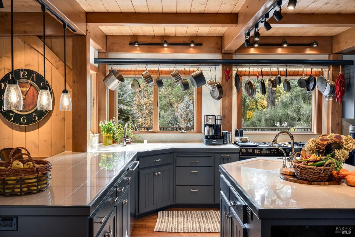 Close-up view of the kitchen sink, island, and windows overlooking trees.