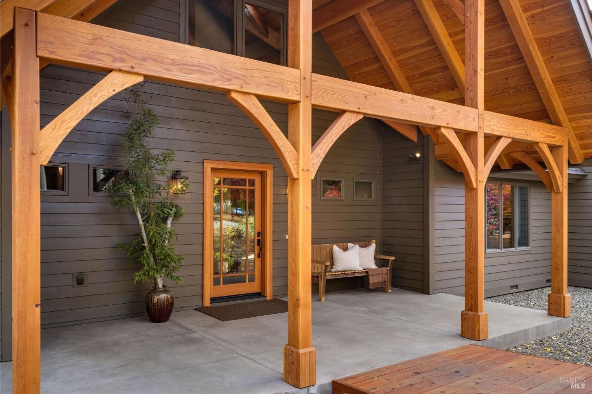 Covered entryway with wooden beams and a front door leading to a house.