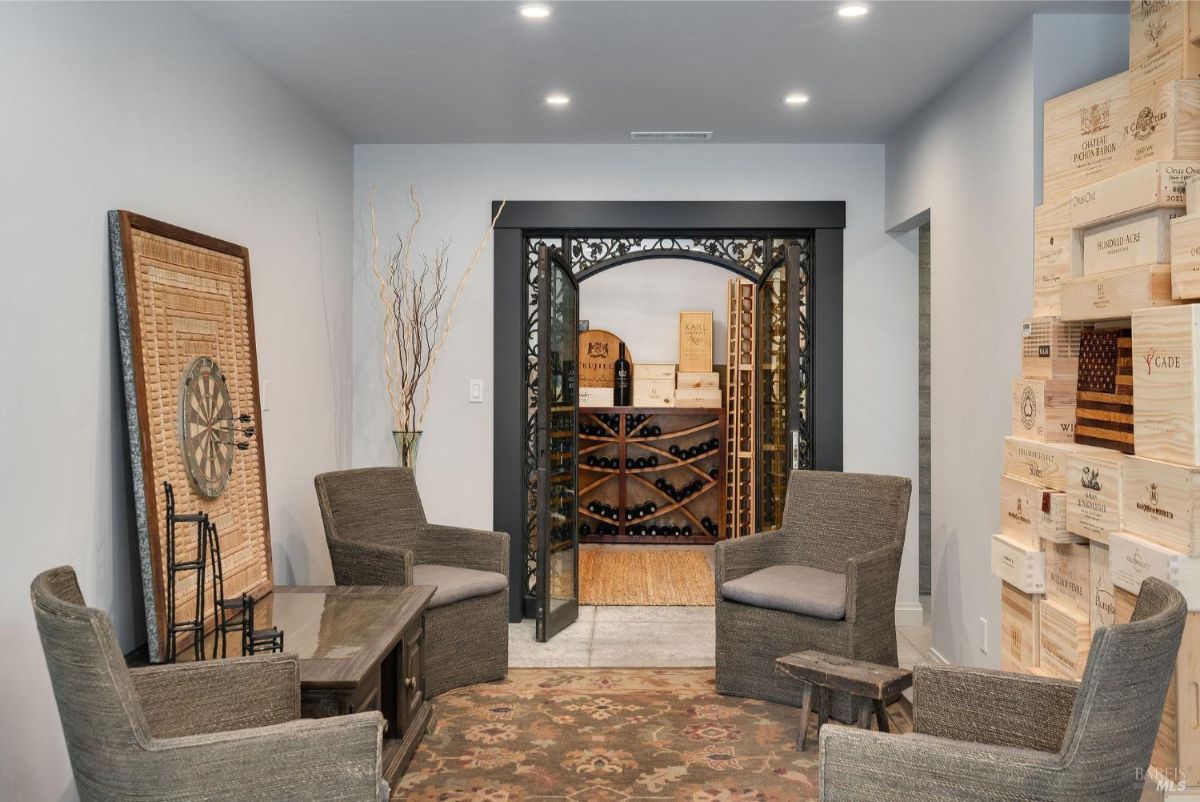 Wine cellar area with seating, wooden wine racks, and an ornate door leading to the wine storage.