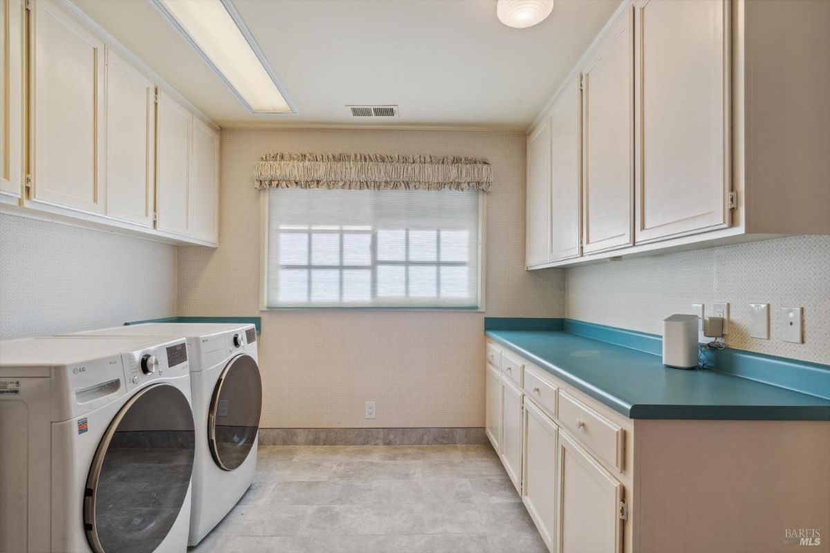 Laundry room with built-in cabinets, turquoise countertops, and modern washer and dryer units.