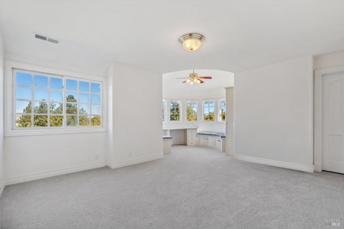Unfurnished bedroom with large windows and an alcove with built-in seating and cabinetry.
