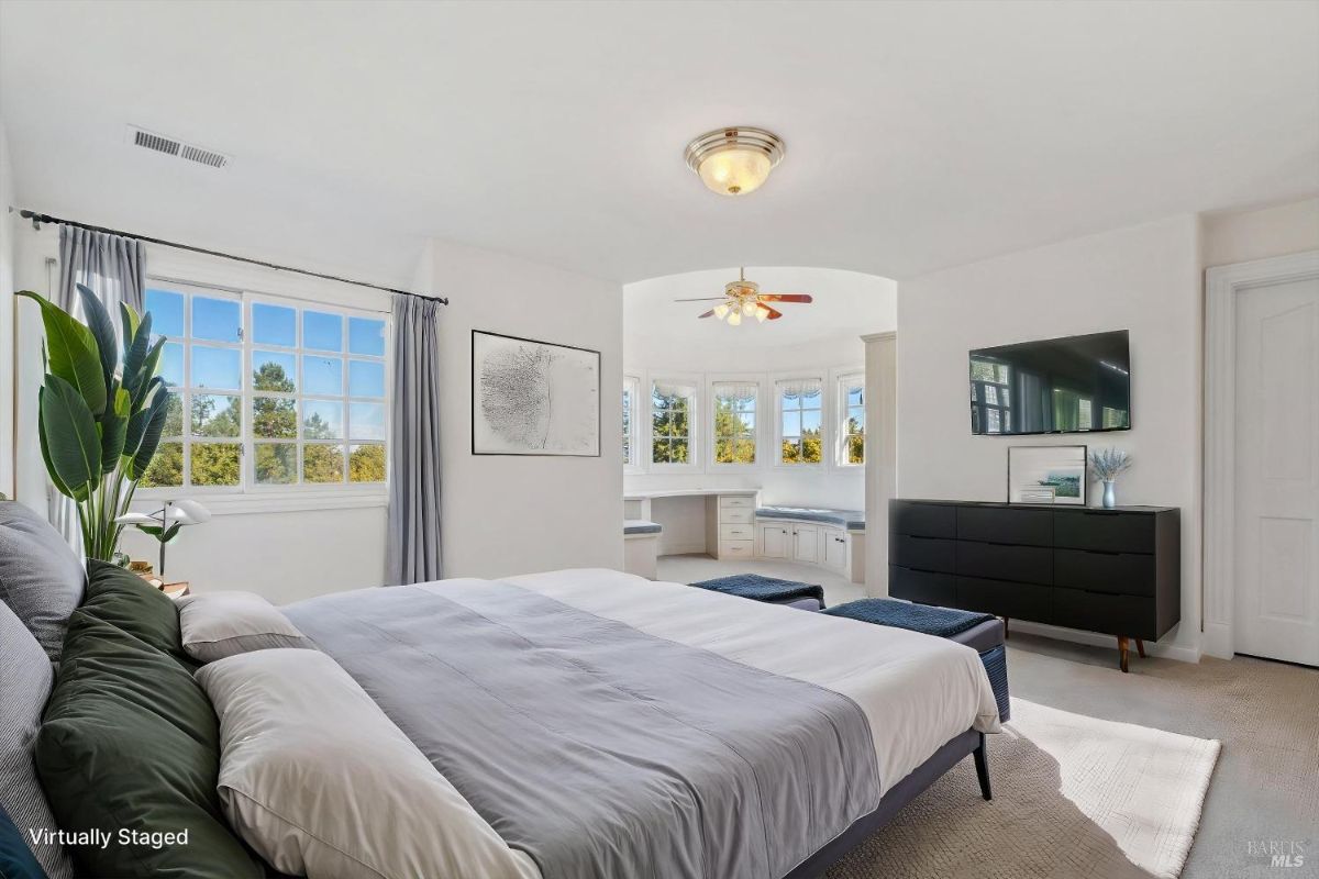 Bedroom featuring large windows, neutral decor, and an alcove with built-in seating and storage.