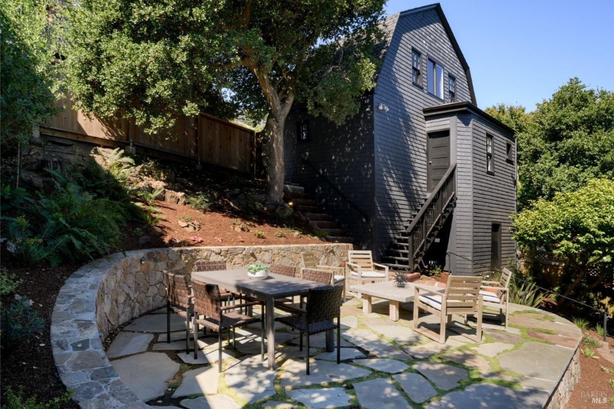 Backyard patio has a stone retaining wall, patio furniture, and a dining table.
