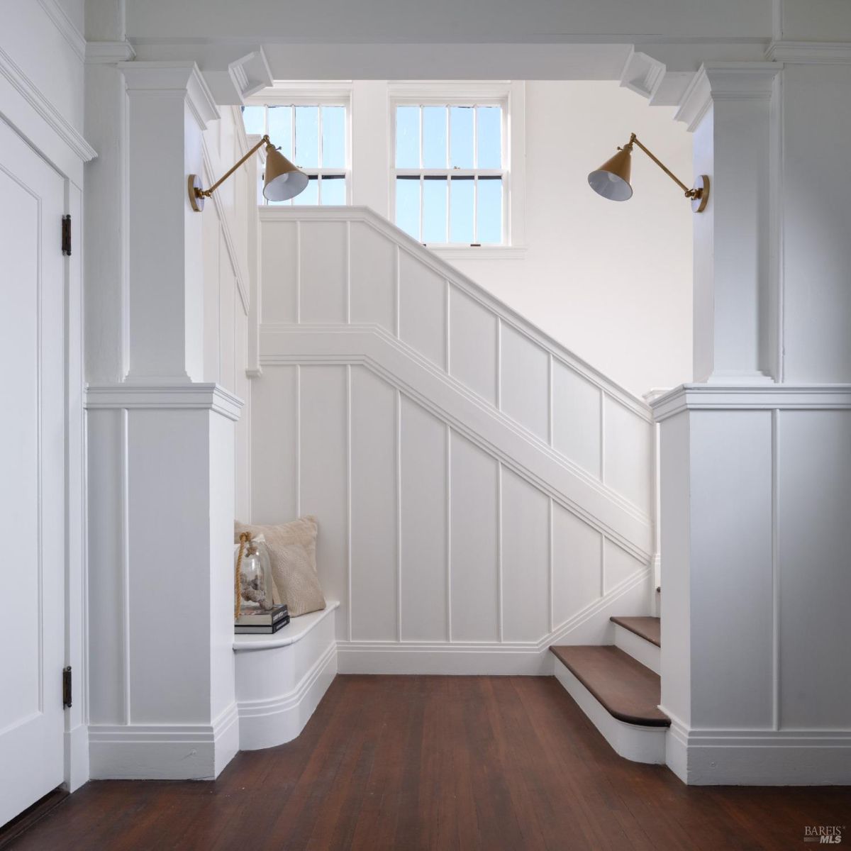 Stairwell with white wainscoting, dark hardwood floors, and a small built-in bench.