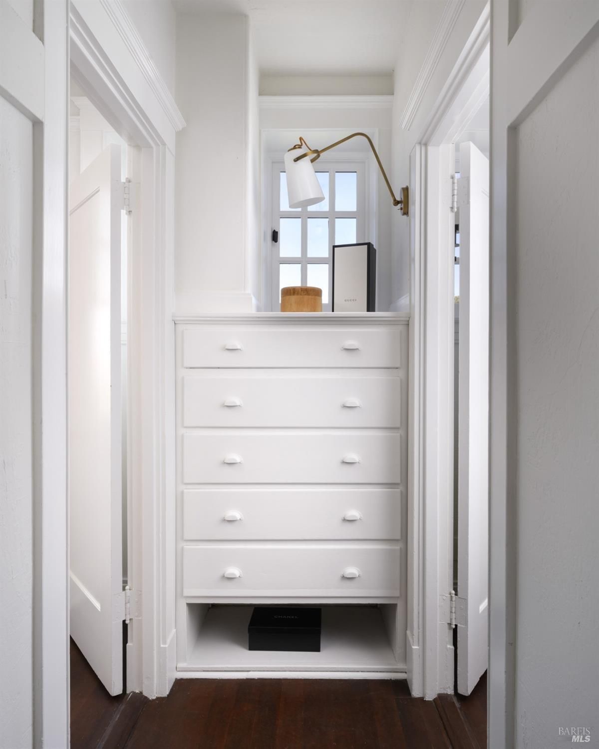 Hallway with white walls, a built-in chest of drawers, and a window.