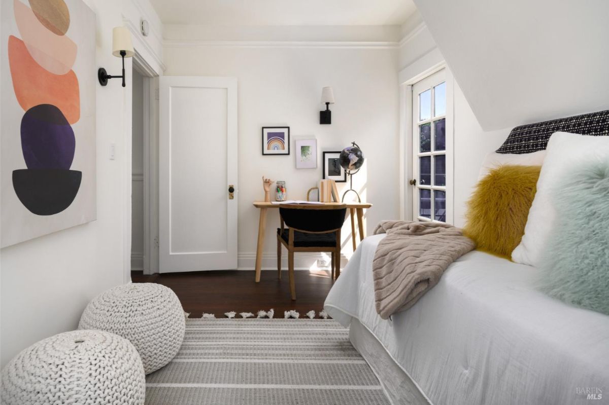 Bedroom with white walls, a small desk and chair, a bed, and a door leading to a balcony or patio.