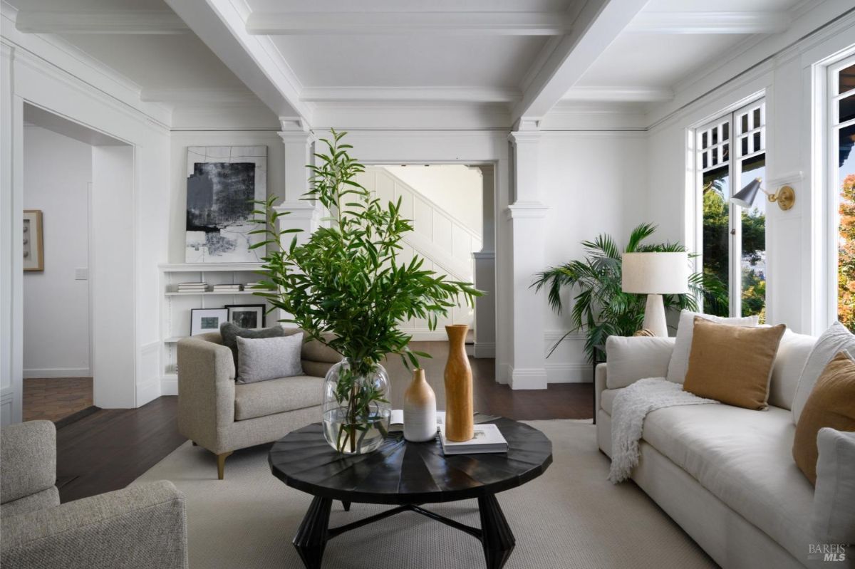 Living room with a minimalist aesthetic, featuring a white couch, a dark coffee table, and a large window with a view of the outdoors.