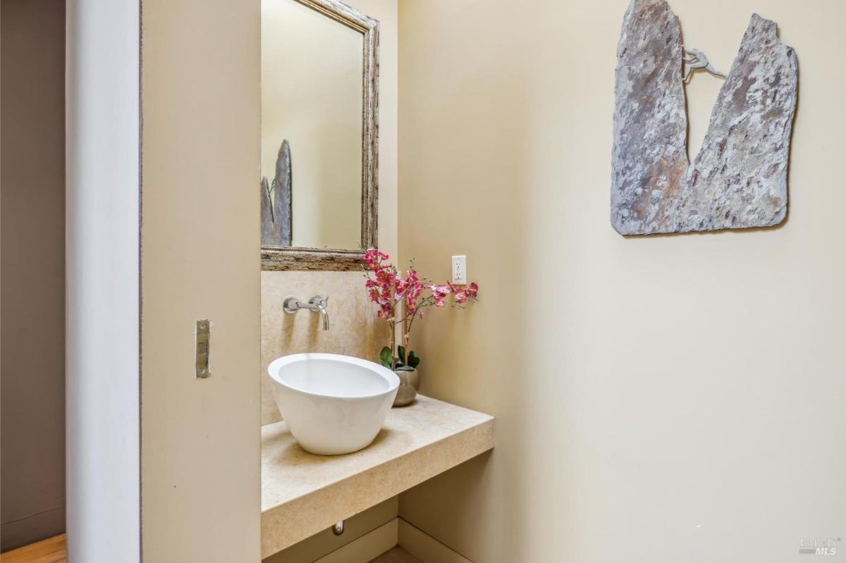 Bathroom with a minimalist sink and a decorative mirror on the wall.