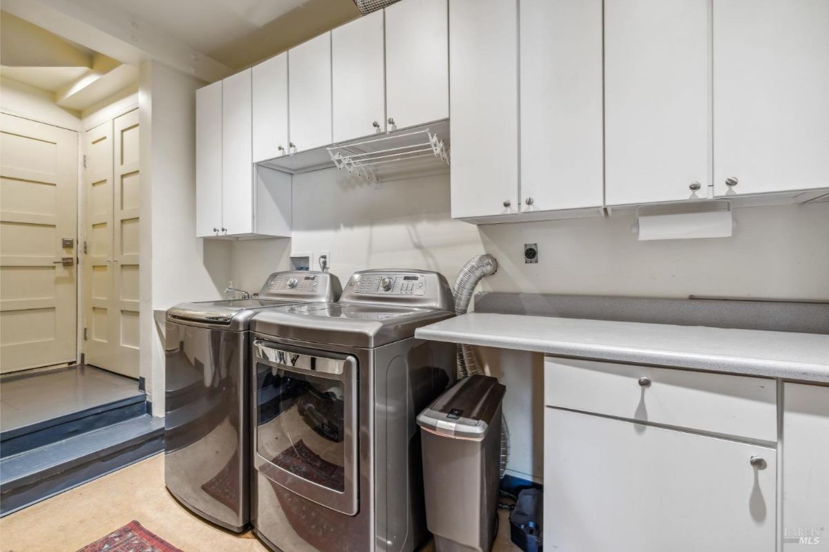 Laundry room featuring stainless steel appliances and a countertop workspace.