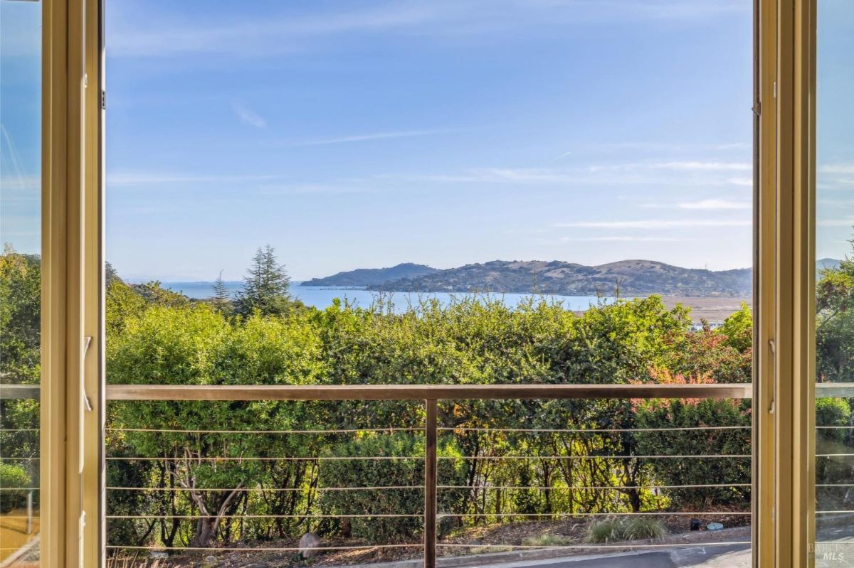 Panoramic view of hills and water as seen through a glass-paneled window.