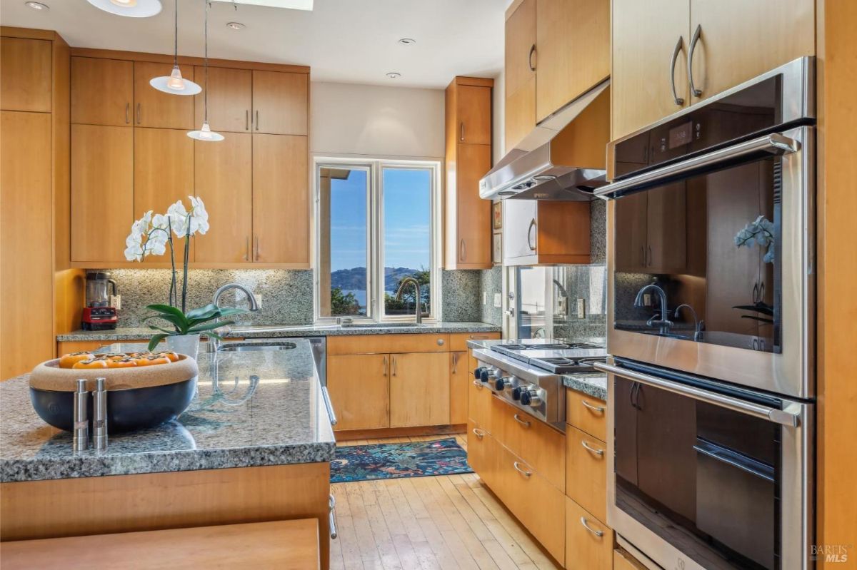 Modern kitchen with light wood cabinets, granite countertops, and stainless steel appliances.